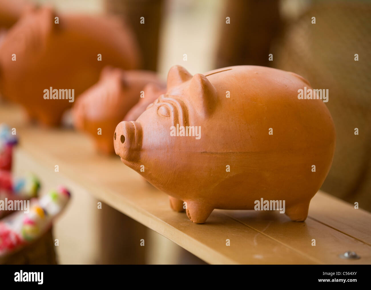 Clay piggy bank sitting on top of shelf Stock Photo