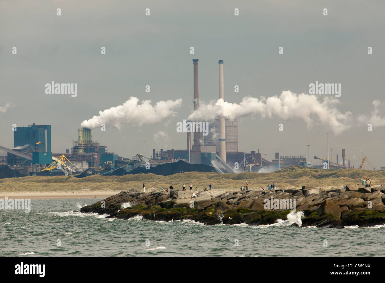 The Netherlands, IJmuiden, Fishermen on pier. Background Tata Steel factory, blast furnaces. Stock Photo