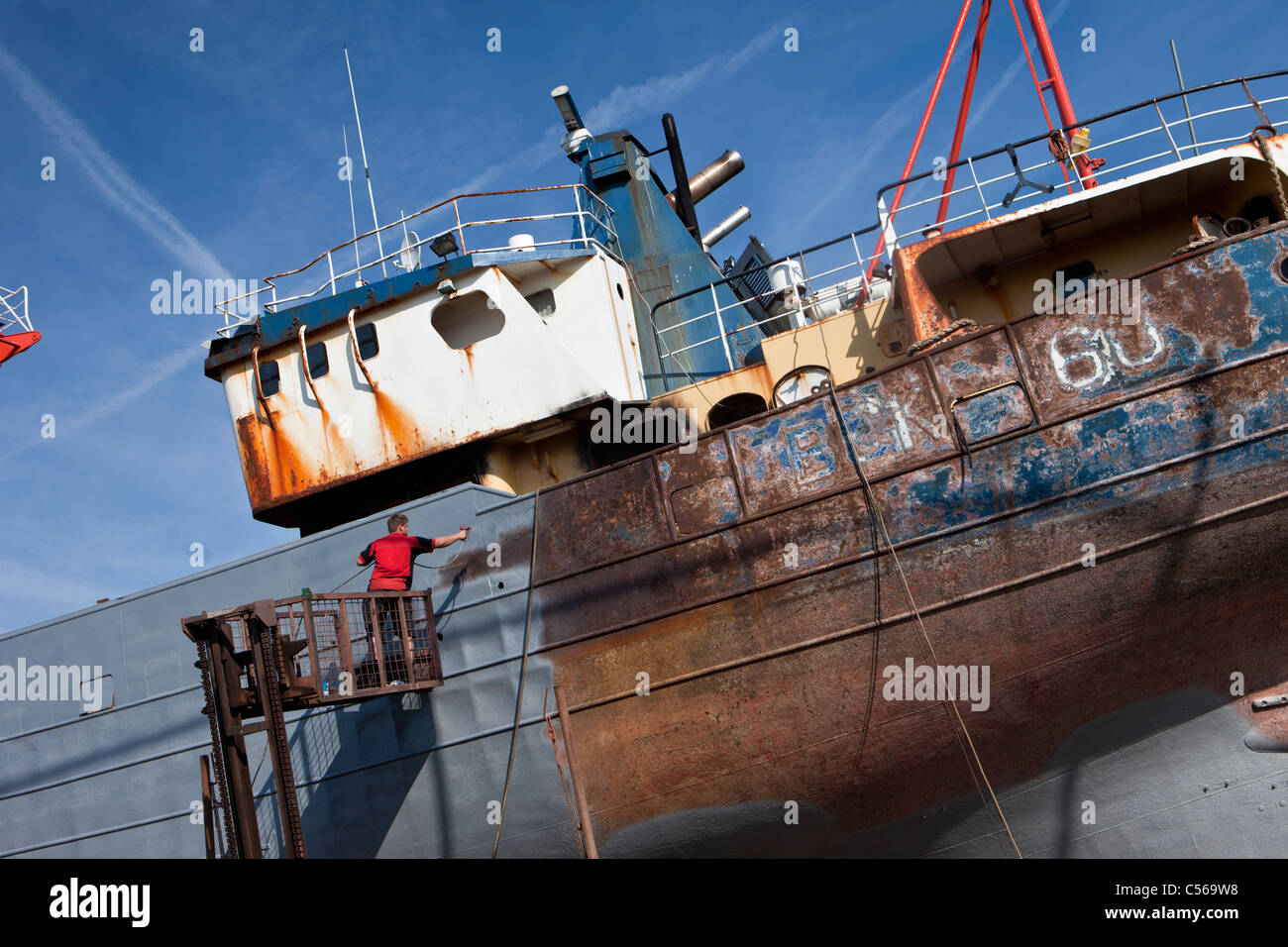 The Netherlands, IJmuiden, Man painting boat in shipyard. Stock Photo