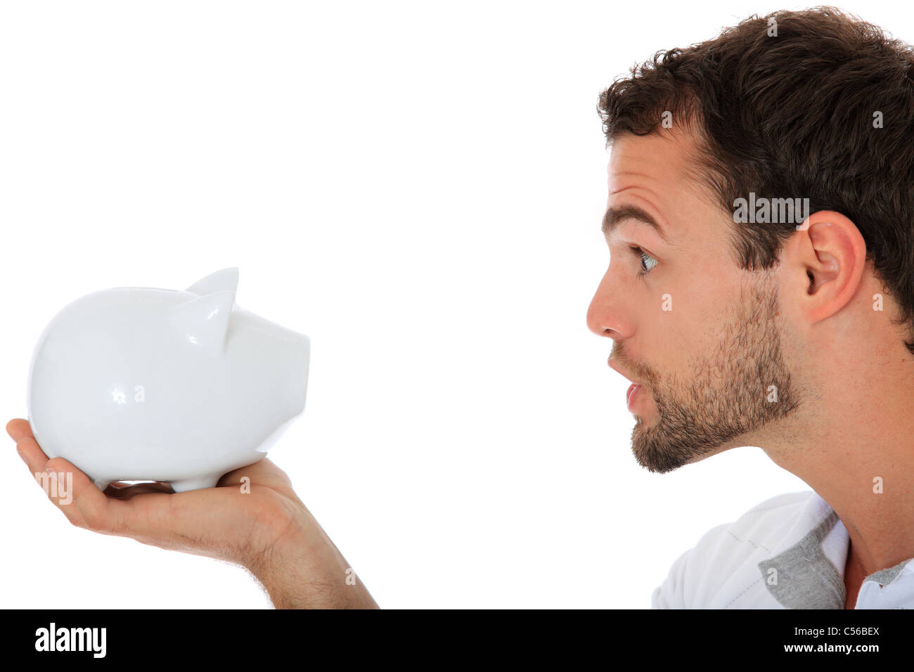 Young guy yells at his piggy bank. All on white background. Stock Photo