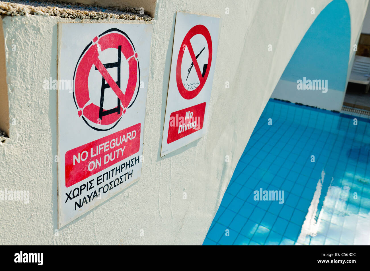 Signs by a swimming pool 'No lifeguard on Duty' (also in Greek) and 'No Diving' Stock Photo