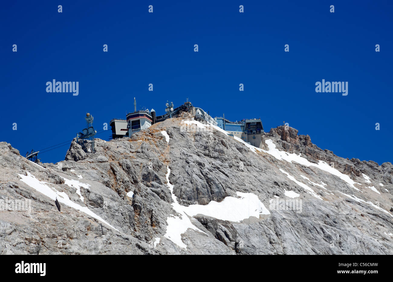 View from Zugspitze glacier plateau to the summit of Zugspitze. Cable car station,  restaurants, observation decks, golden cross Stock Photo