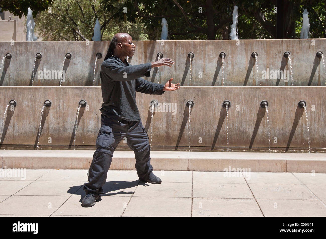Man practicing Tai Chi in public in front of a fountain. Stock Photo