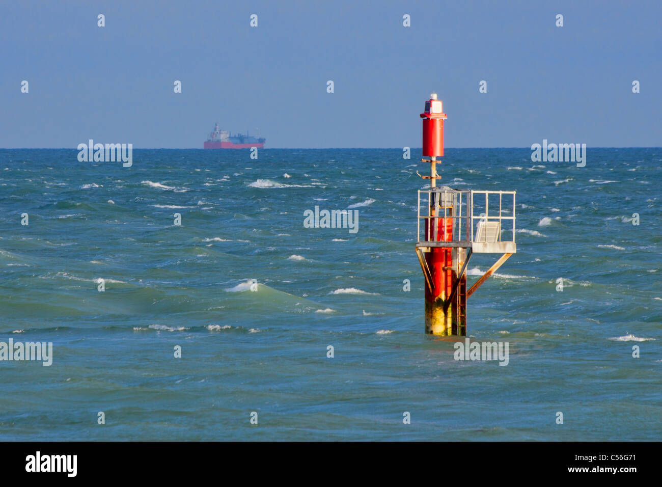 Red port side navigation channel marker illuminated by the sun in a