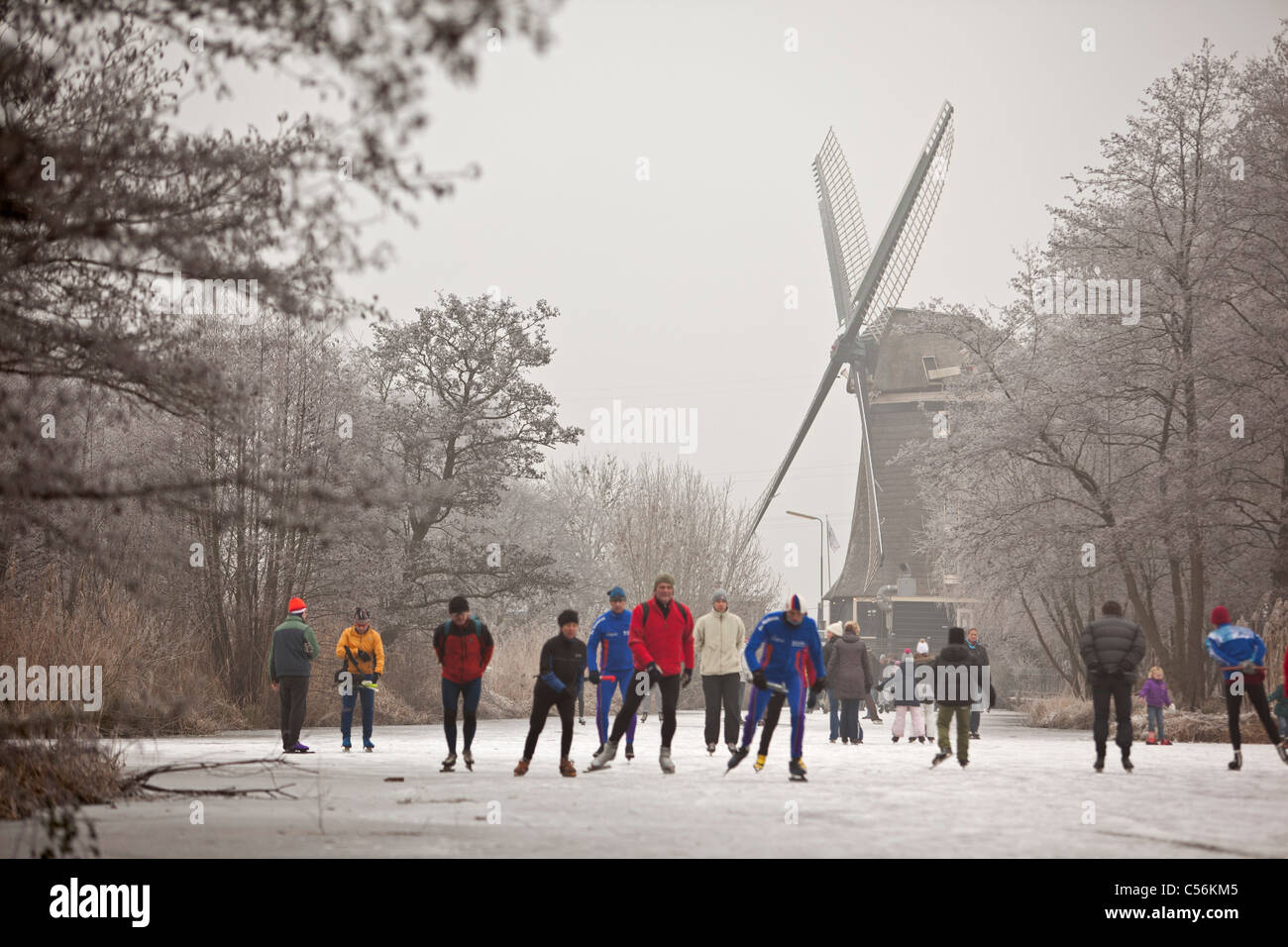 The Netherlands, Ankeveen. People ice skating in front of windmill. Stock Photo