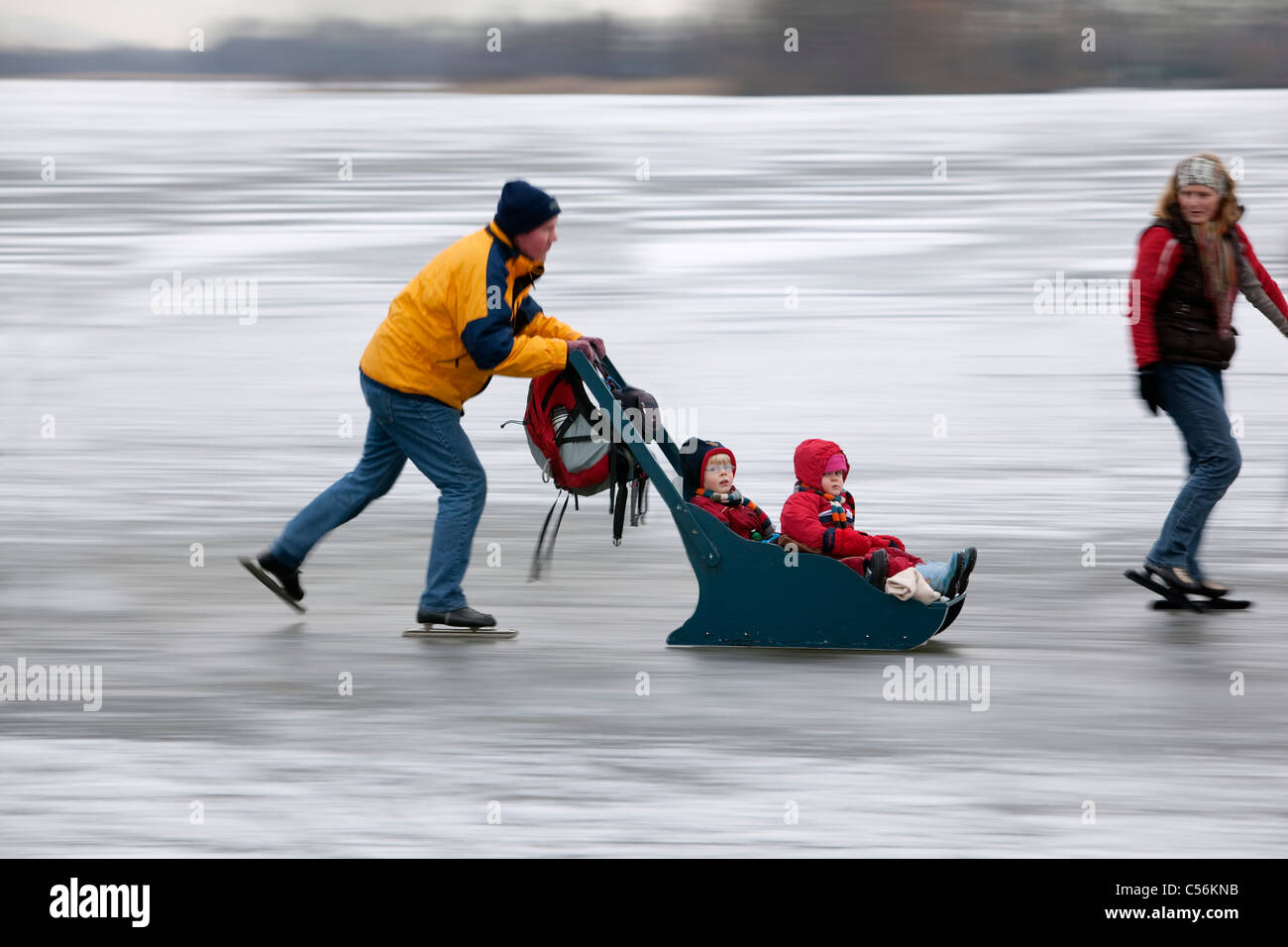 The Netherlands, Ankeveen. Family with sledge ice skating. Motion blurred. Stock Photo