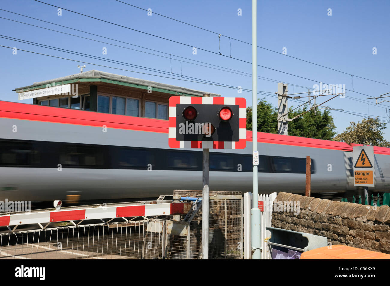 Main line level crossing with red lights flashing at a high speed Virgin Express train. Hest Bank, Lancashire, England, UK, Britain. Stock Photo