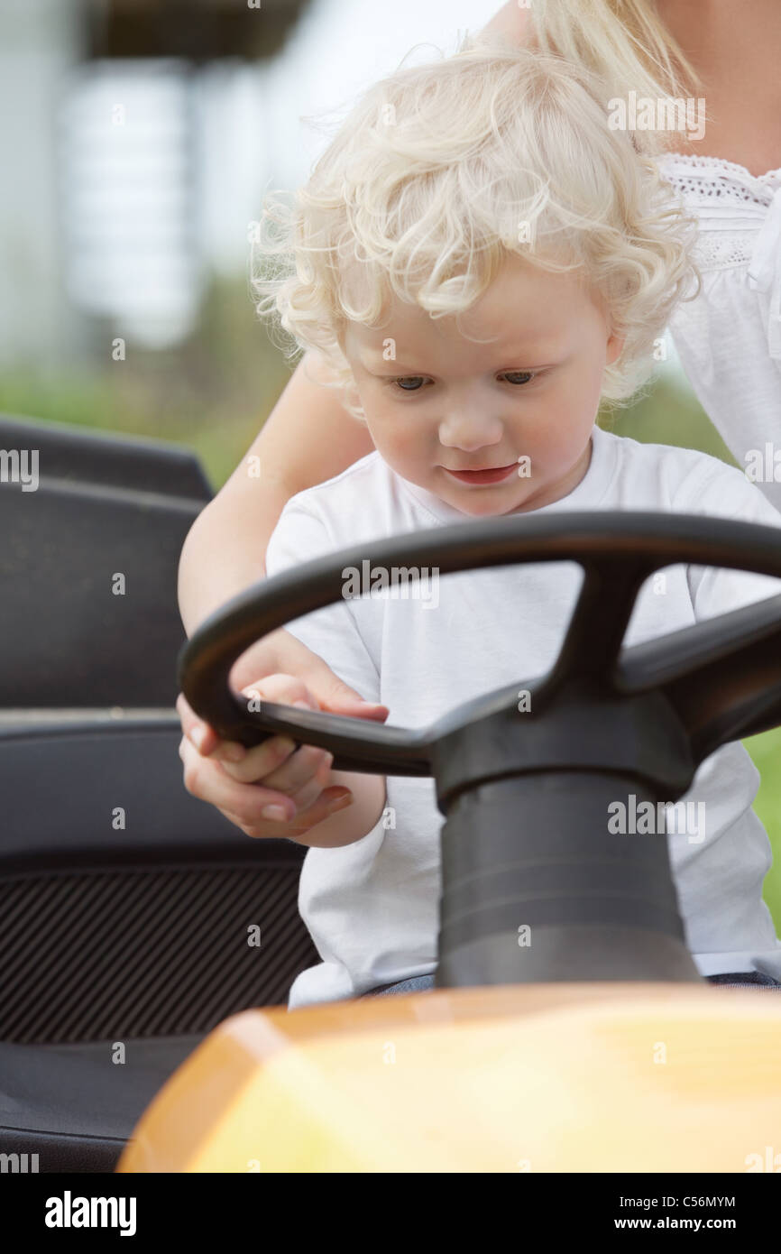 Young boy holding wheel on garden tractor Stock Photo Alamy