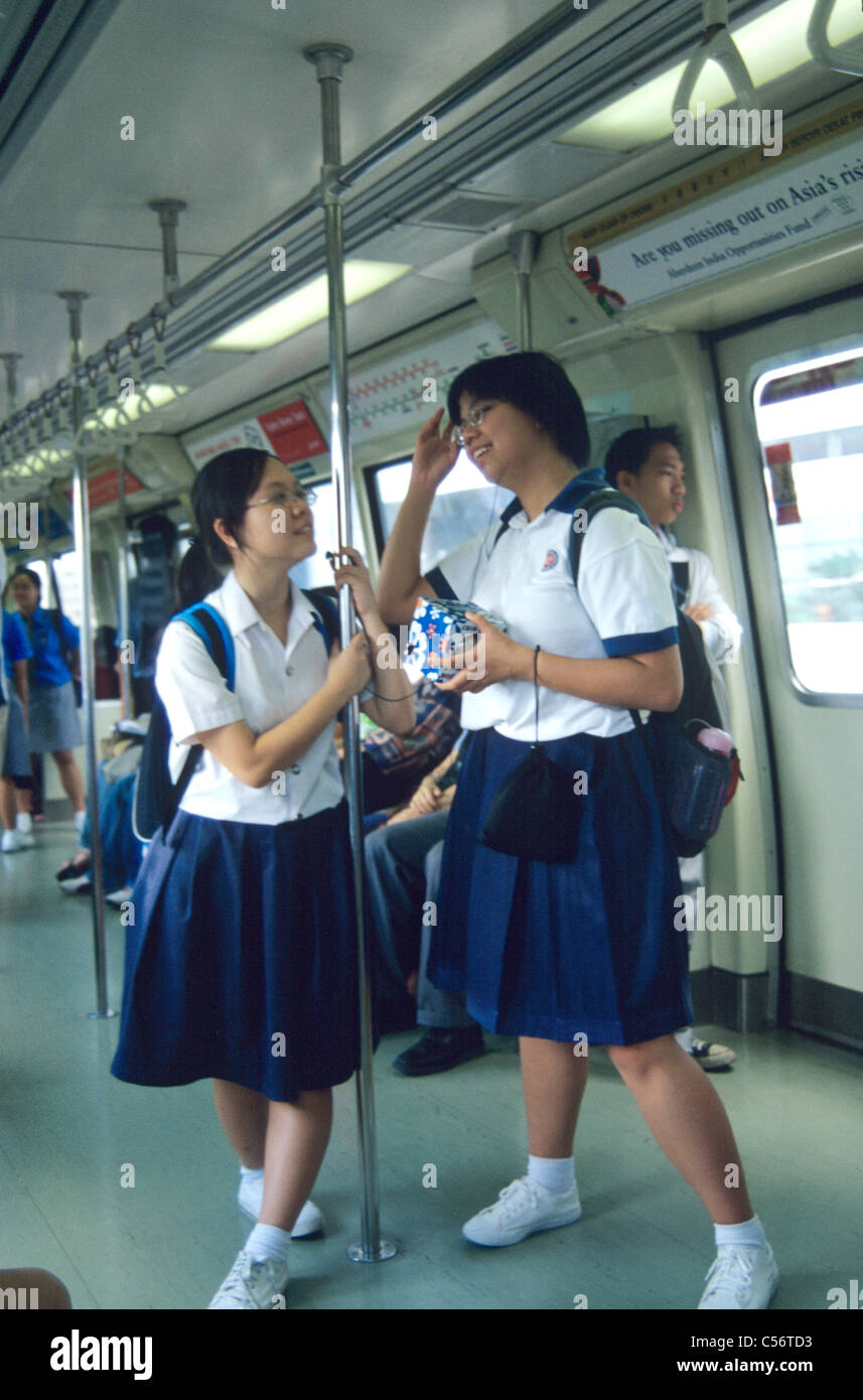 Two Singaporean school girls in uniforms talking on the local mass transit  MRT Stock Photo - Alamy