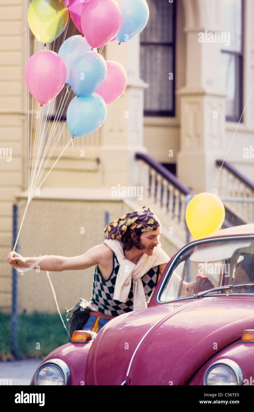 hippie passes out free balloons to woman in Volkswagen in Haight Ashbury in the sixties San Francisco Stock Photo