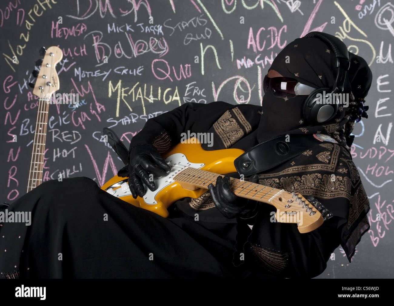 Female dressed in full Purdah playing lead guitar in a Heavy Metal Band Stock Photo