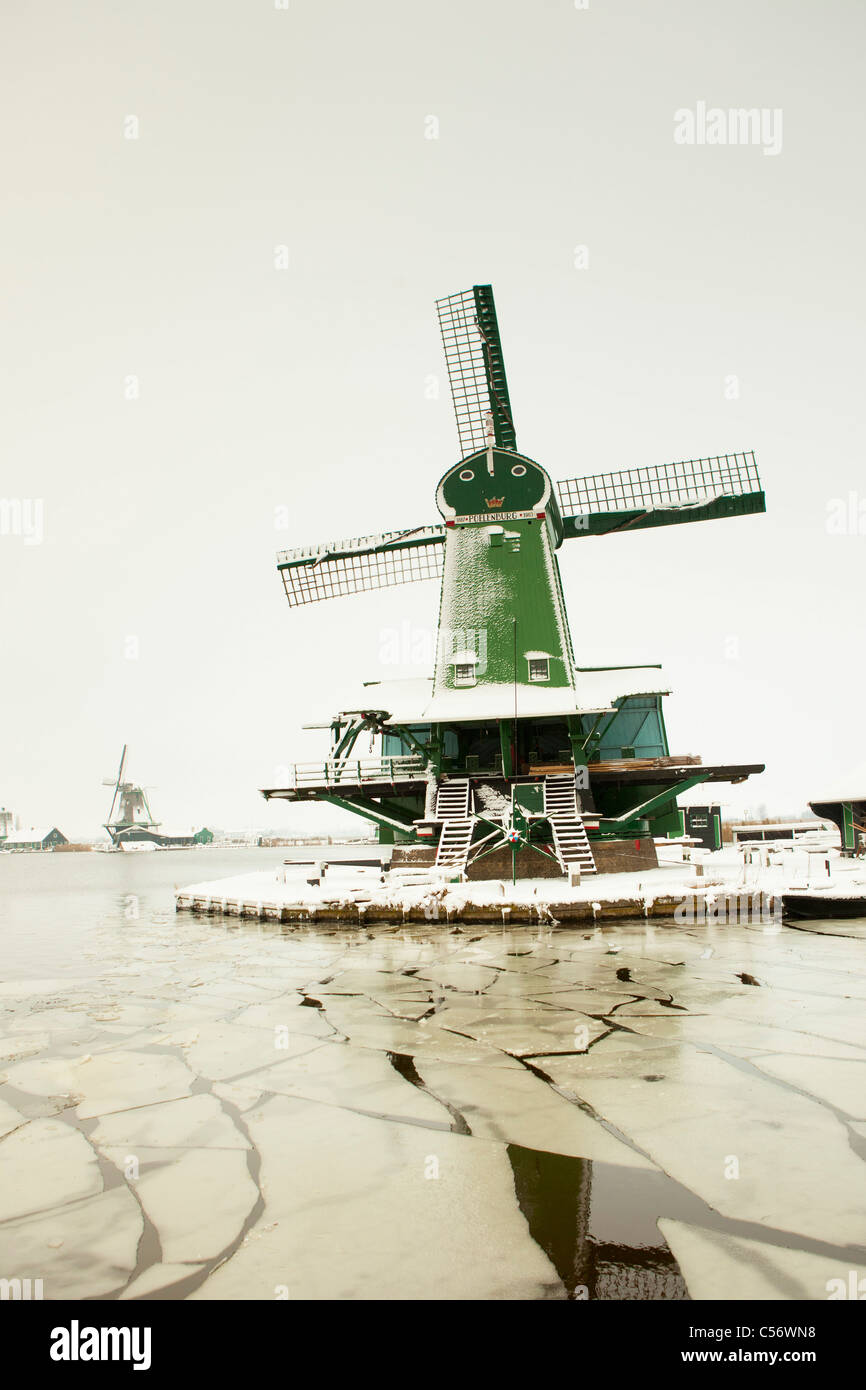 Zaanse Schans, village on the banks of the river Zaan with characteristic green wooden houses, historic windmills. Winter, snow. Stock Photo