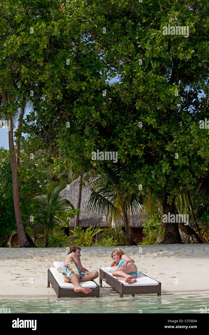 Couple relaxing on daybeds at beach Stock Photo
