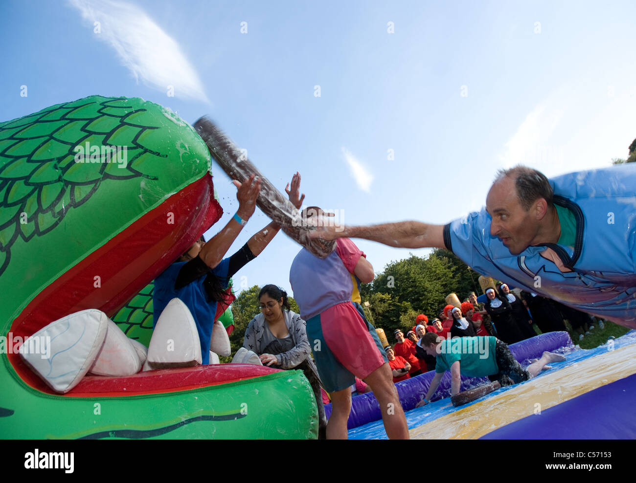 its a knock out competitor trying to knock the teeth out of an inflatable dinosaur Stock Photo