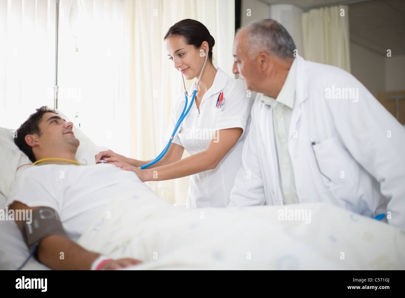 Doctor and nurse tending to patient Stock Photo - Alamy