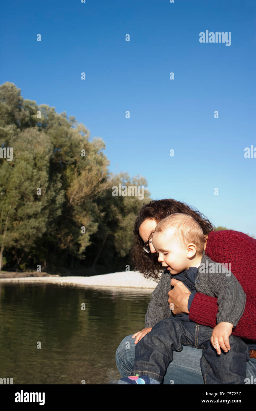 Mother holding baby by creek Stock Photo