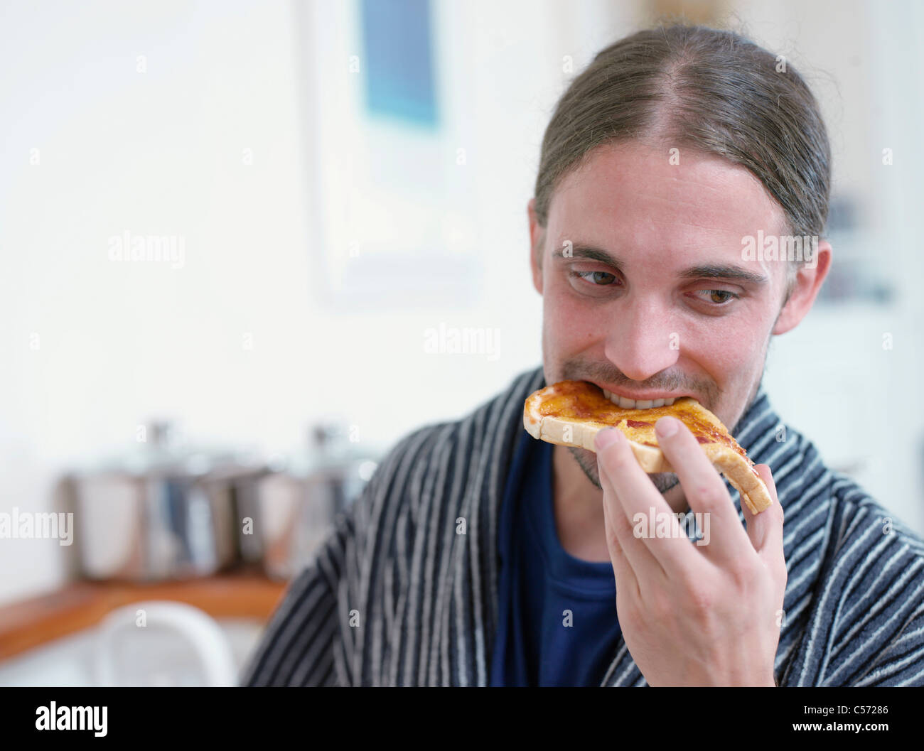 Man eating toast in kitchen Stock Photo Alamy