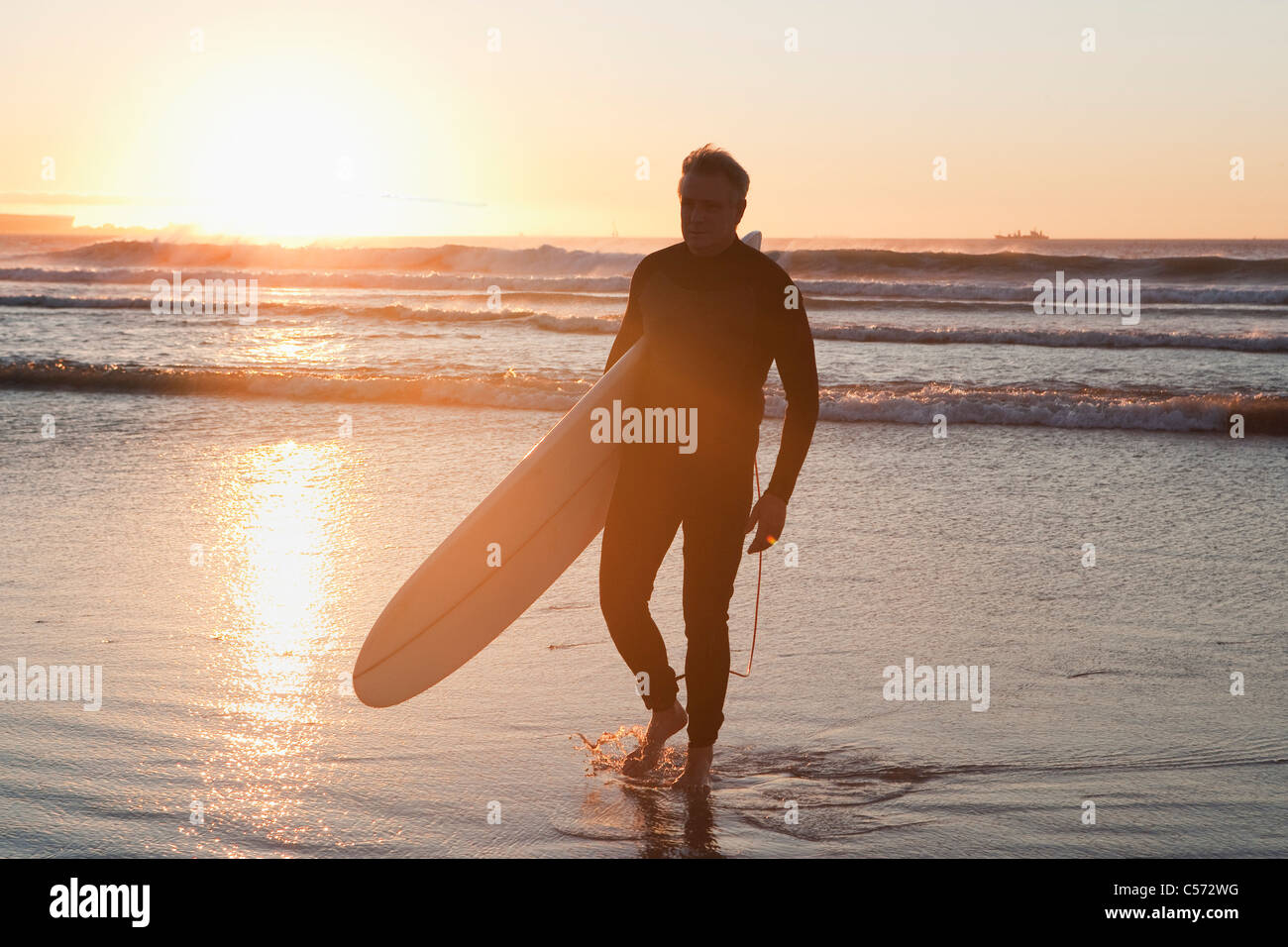 Surfer walking in water Stock Photo