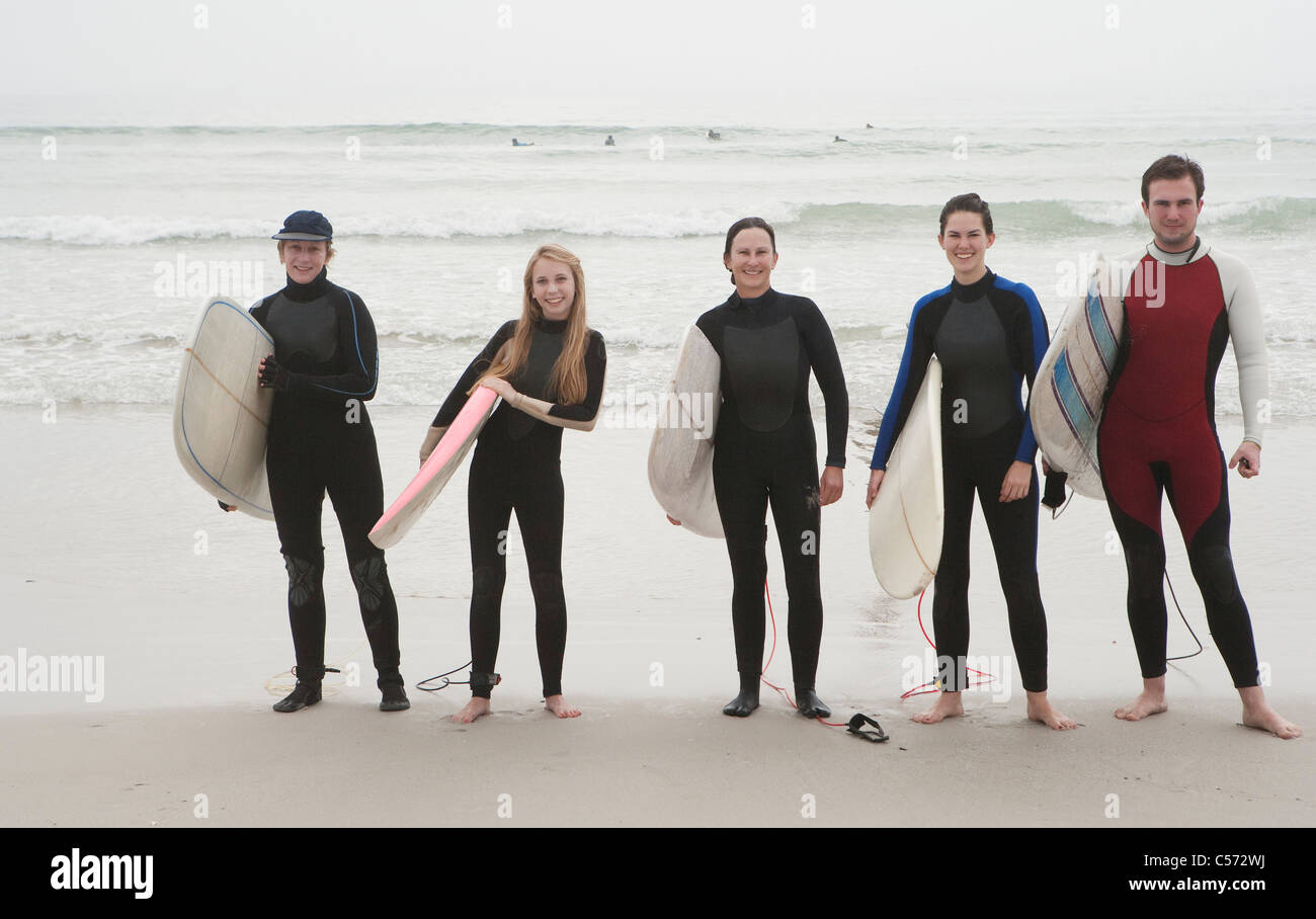 Family of surfers standing on beach Stock Photo