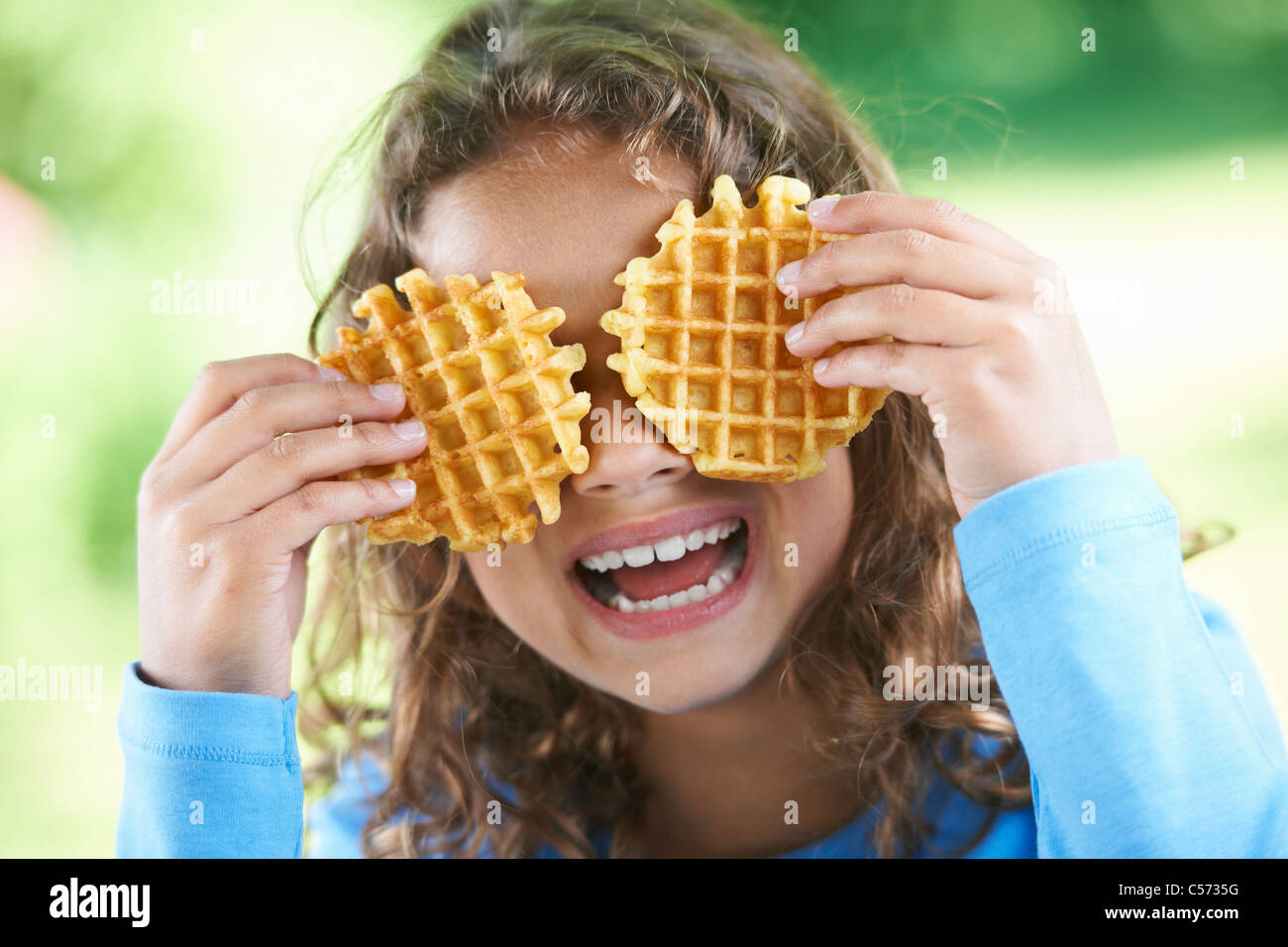 Smiling girl playing with waffles Stock Photo