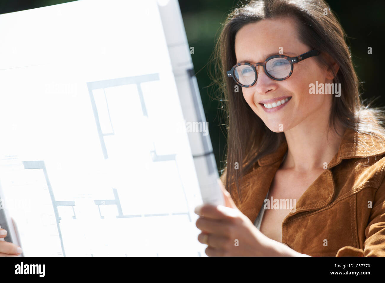 Woman reading blueprints outdoors Stock Photo