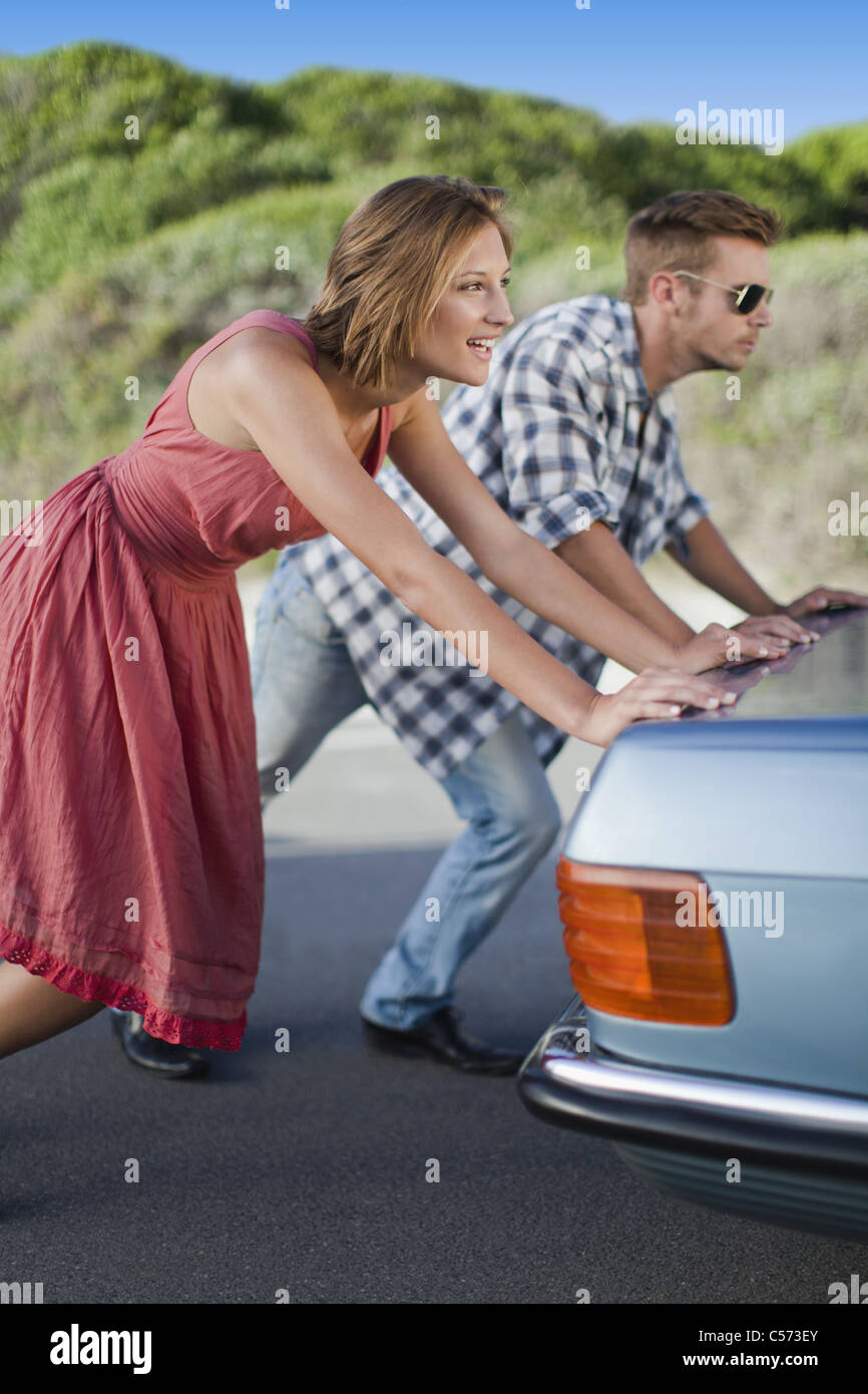 Couple pushing broken down car Stock Photo