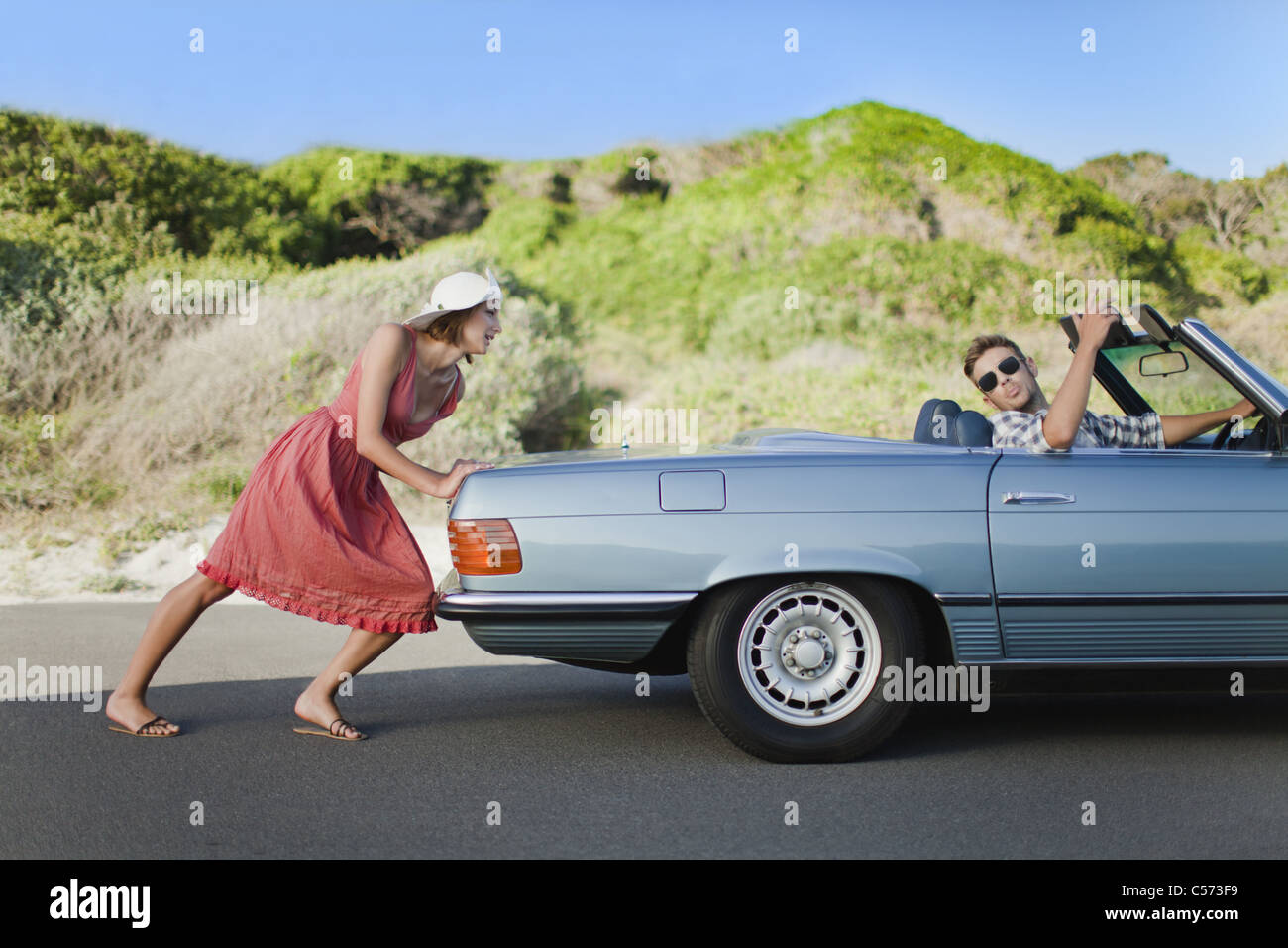 Woman pushing car as boyfriend steers Stock Photo Alamy