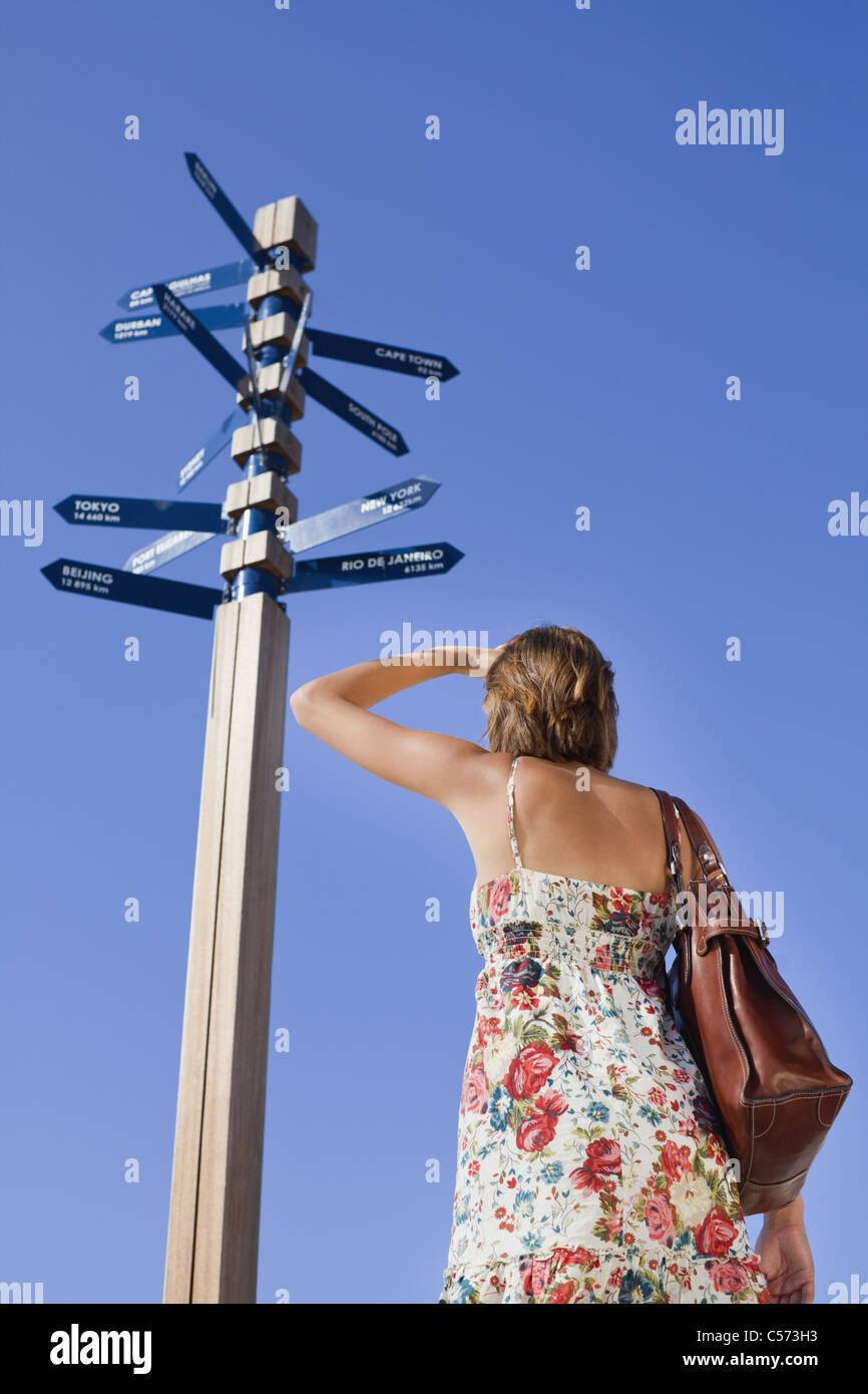Woman reading directions at crossroads Stock Photo - Alamy