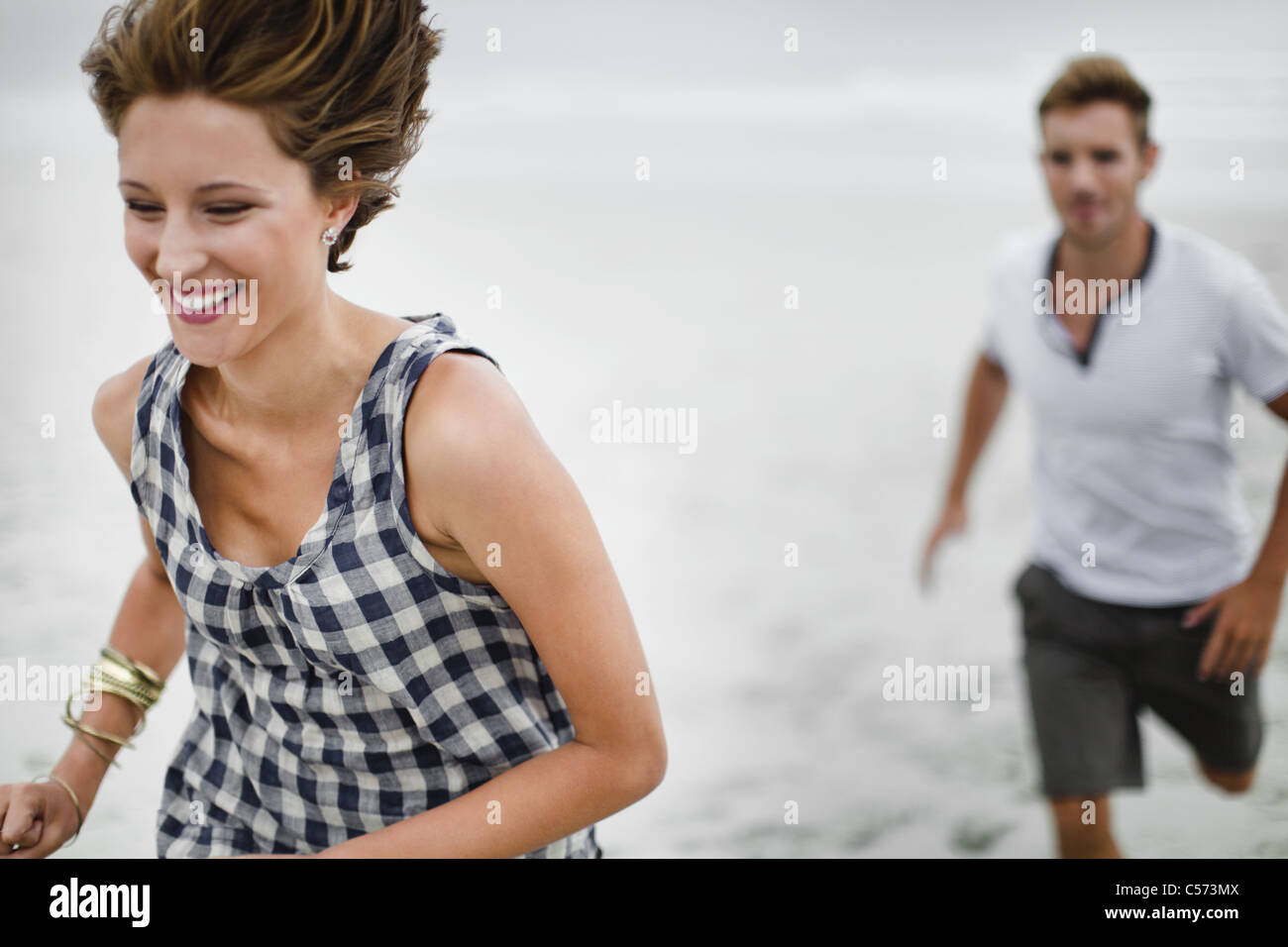 Couple chasing each other on beach Stock Photo
