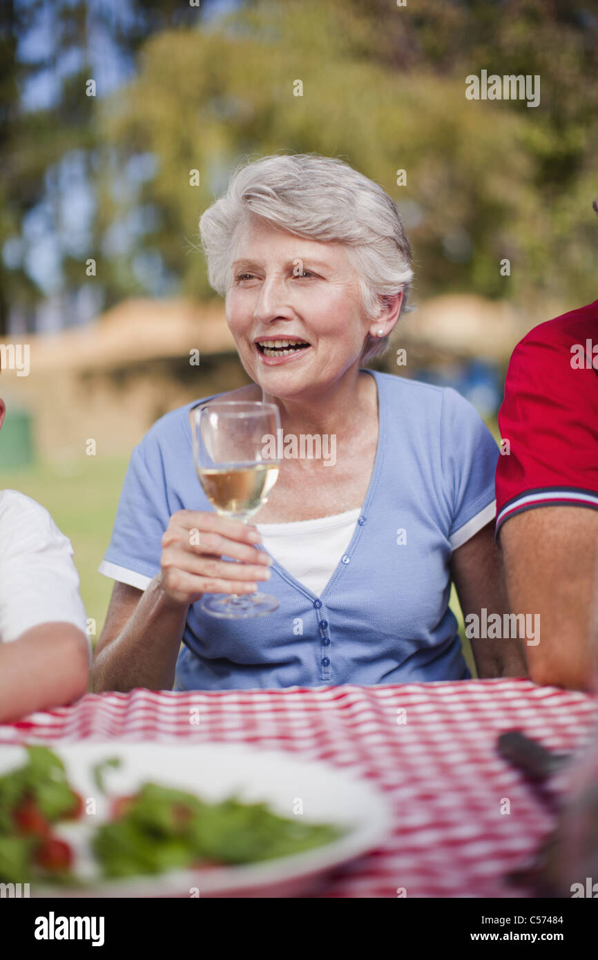 Older woman drinking at picnic table Stock Photo