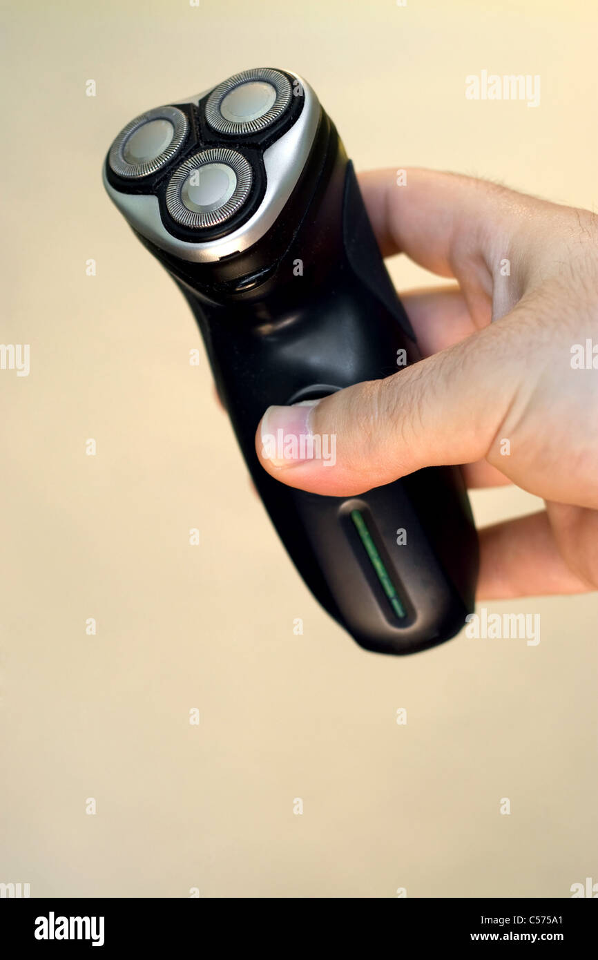 A hand holding an electric shaver isolated over a solid color