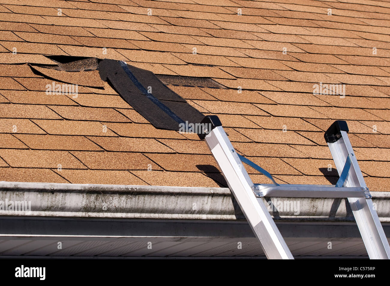 Fixing damaged roof shingles. A section was blown off after a storm