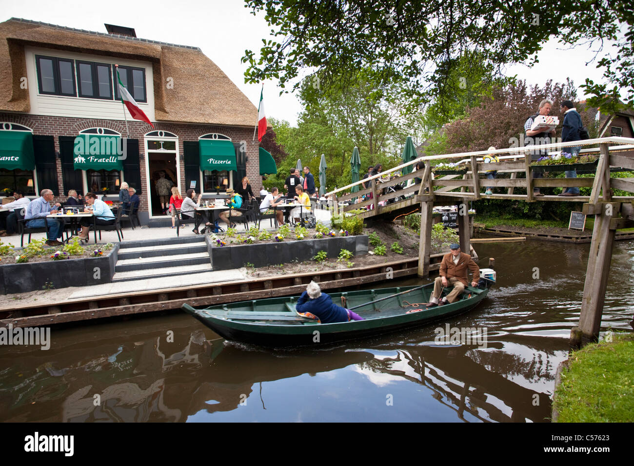 The Netherlands, Giethoorn, Village with almost only waterways. Italian restaurant and outdoor cafe. Boat pasing. Stock Photo