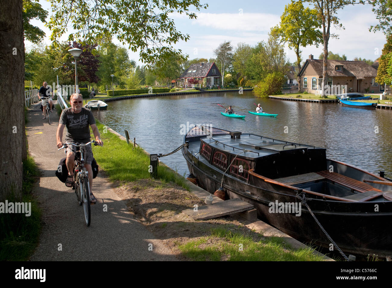 The Netherlands, Giethoorn, Village with almost only waterways. Tourists enjoying kayak ride and cyclists. Stock Photo