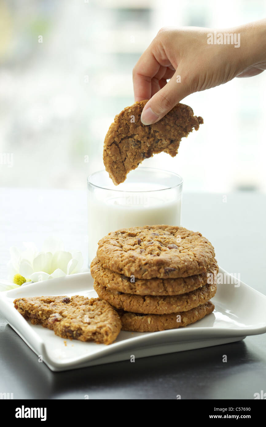 Woman's hand dipping chocolate chip cookie in milk Stock Photo Alamy