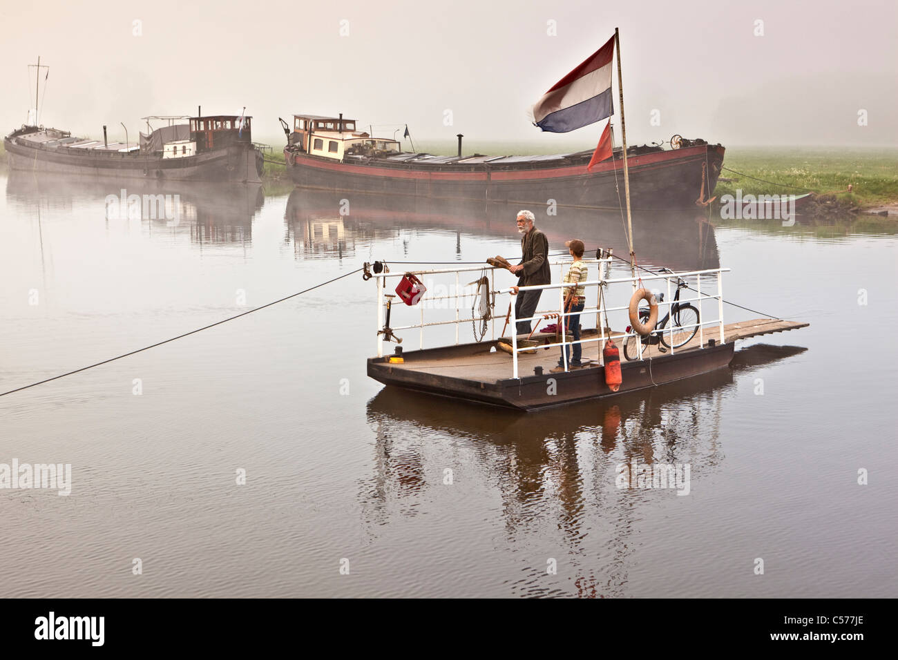 The Netherlands, Haerst, Former cargo boats, Morning mist. Hand driven ferryboat. Stock Photo