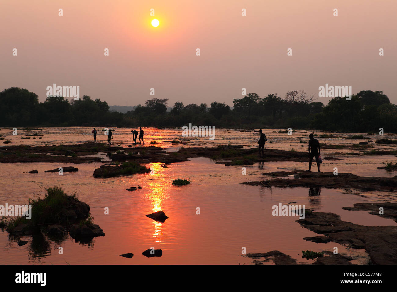 A group of men make an illegal border crossing over a ford in the Zambazi River between Zambia and Zimbabwe. Stock Photo