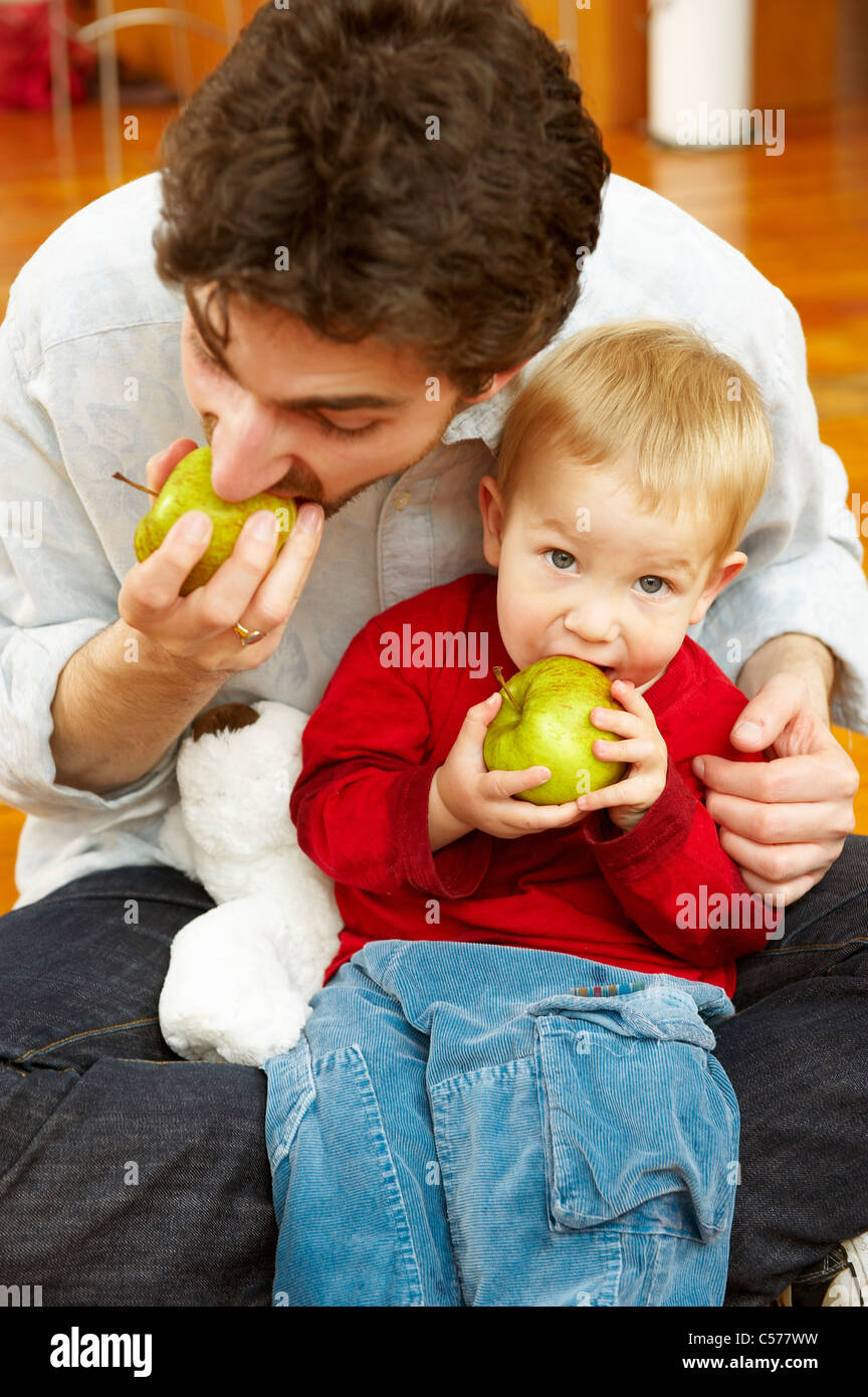 Father and son eating apples together Stock Photo