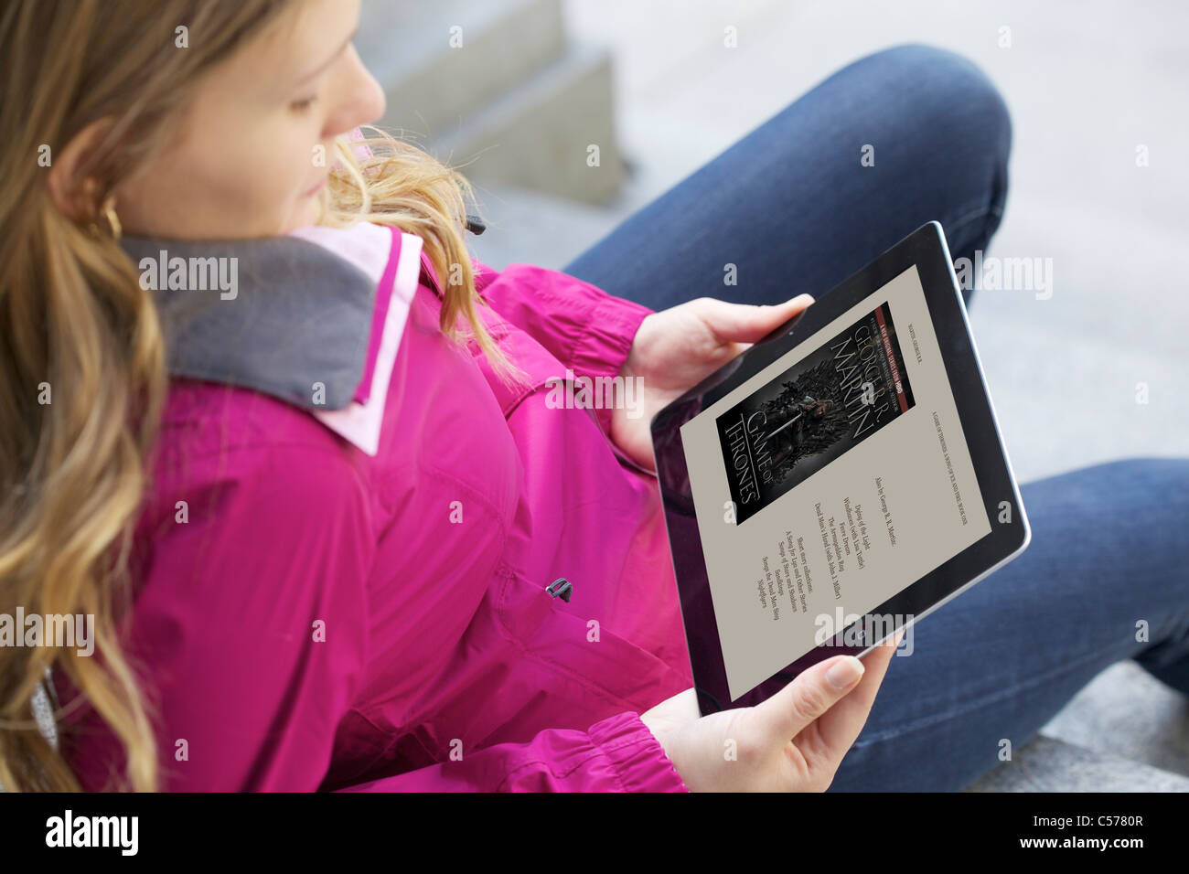 Close up view of a Caucasian young woman reading 'A Game of Thrones' book from Kindle Ipad 2 application Stock Photo
