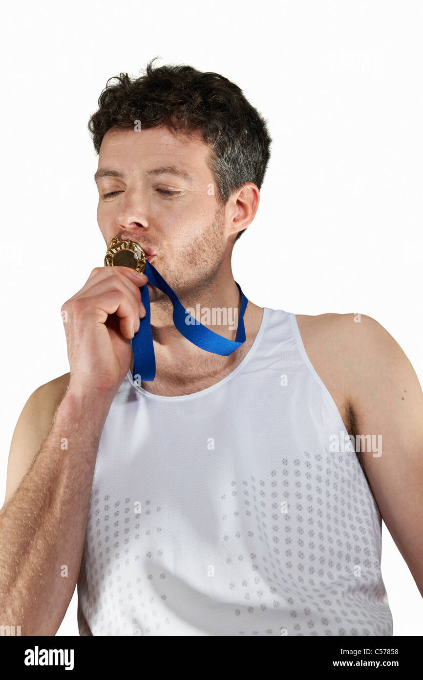 Man in running gear kissing medal Stock Photo