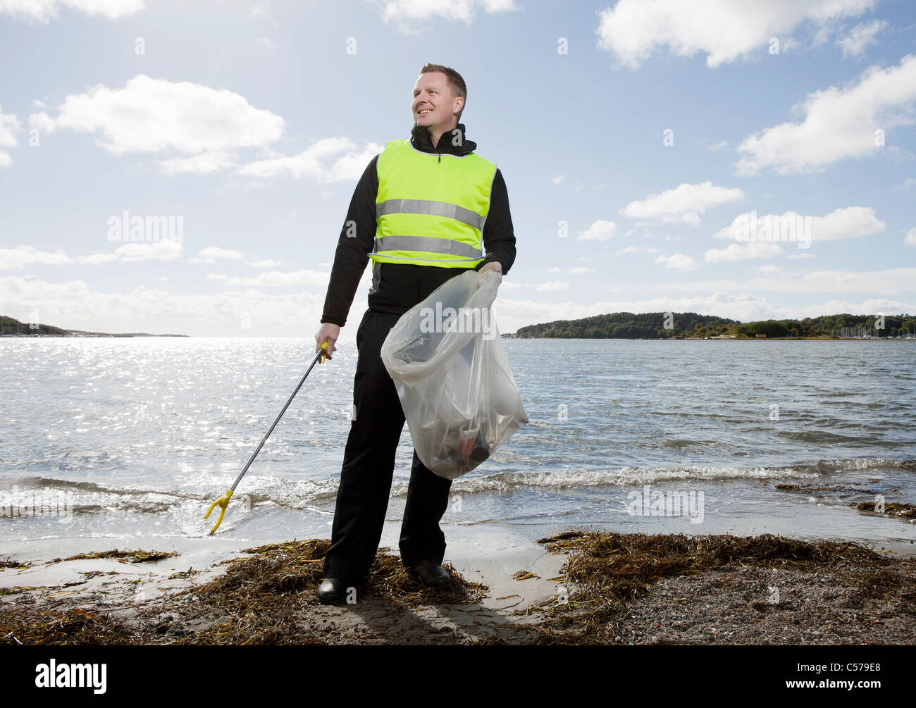 Worker in safety vest cleaning beach Stock Photo Alamy