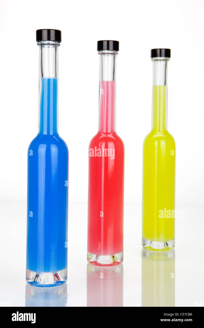 three glass bottles with colored Getra ¤ nken in red, blue, yellow Stock Photo