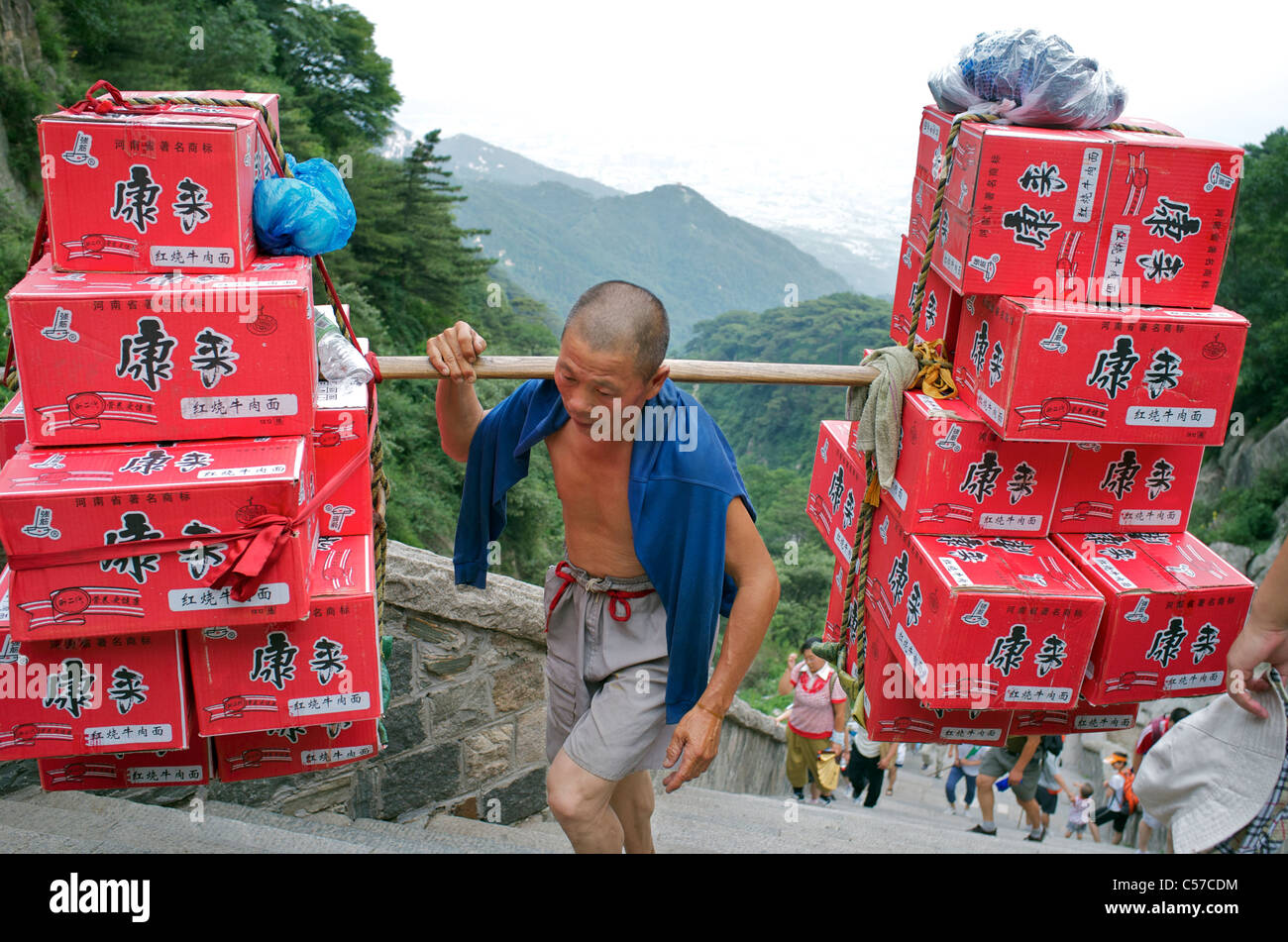 Chinese man carries a load of instant noodles up to Taishan mountain in Shandong, China. 08-Jul-2011 Stock Photo