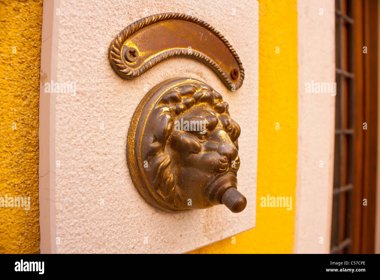 Door bell with lion head on white wall Stock Photo