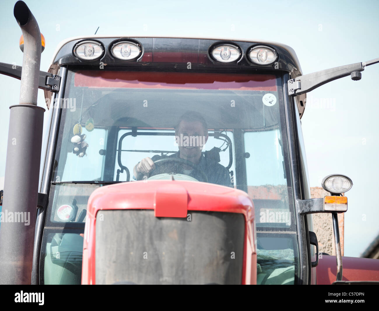 Farmer driving tractor on farm Stock Photo