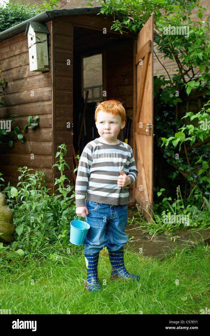 Boy playing with bucket in backyard Stock Photo Alamy