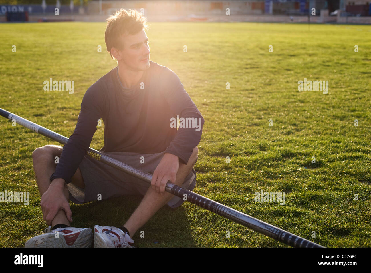 Man sitting with pole on grass Stock Photo