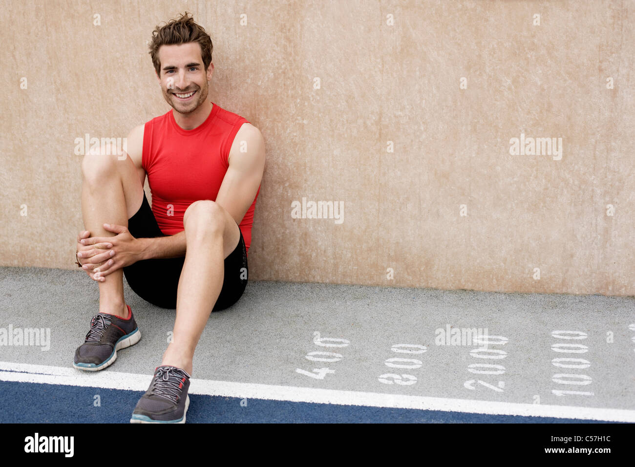 Smiling runner sitting against wall Stock Photo