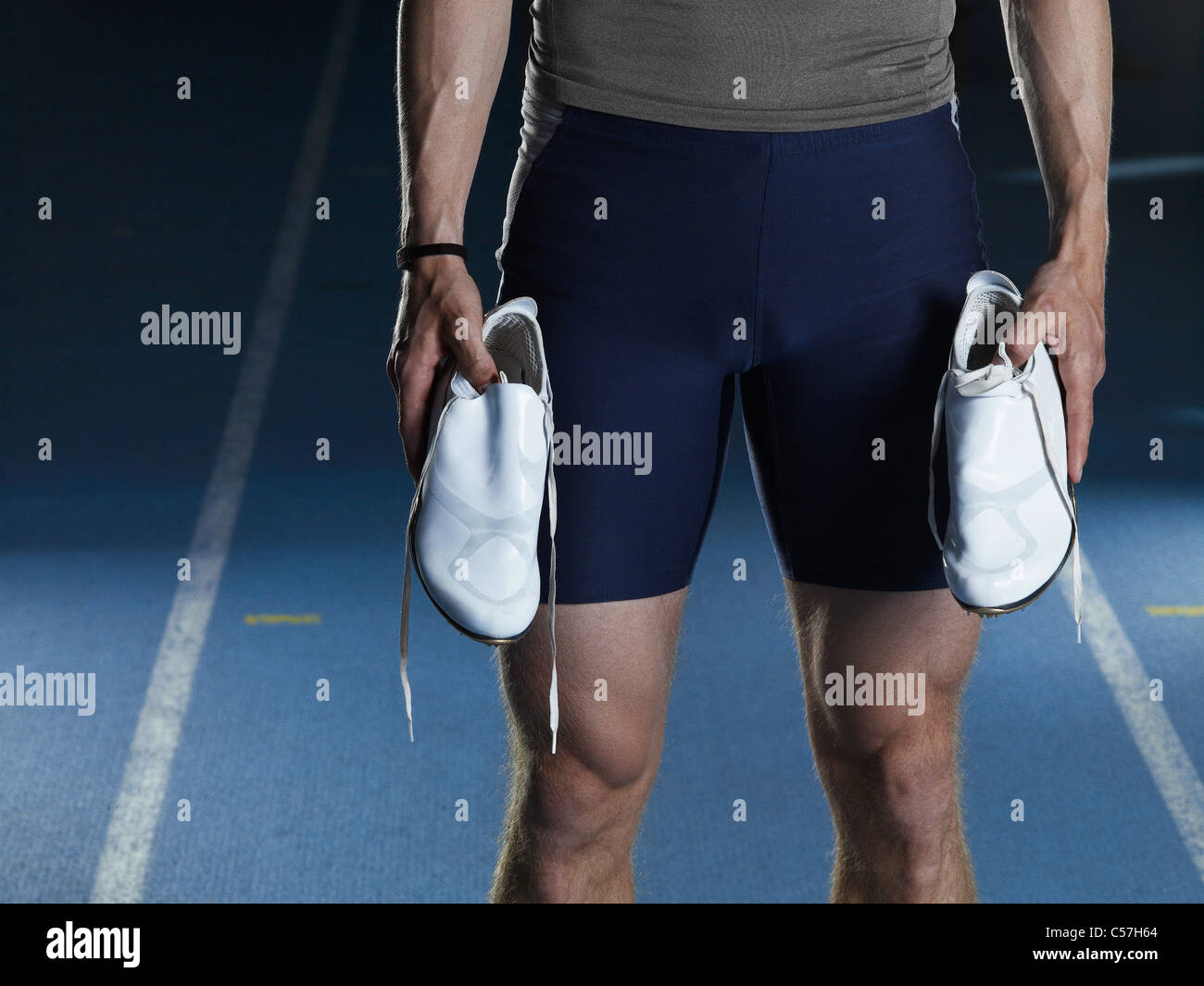 Man carrying running shoes on track Stock Photo