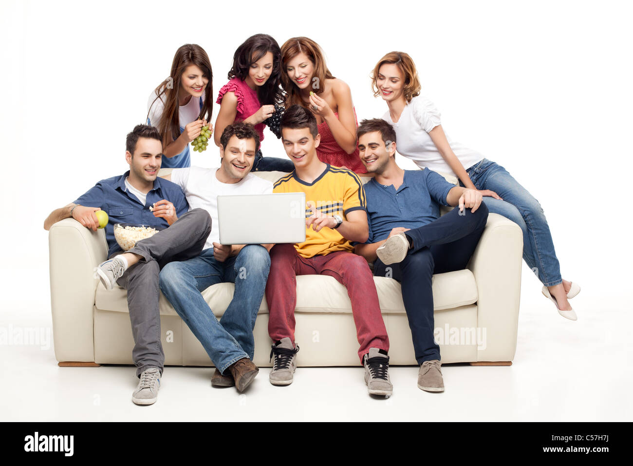 young group of friends sitting on couch smiling at laptop Stock Photo ...